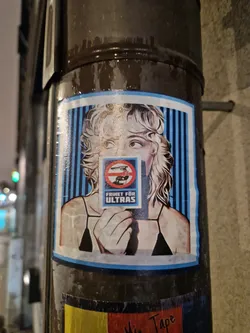 Street sticker A sticker featuring a woman holding a sign that says "Freedom for Ultras". The sign also contains an image of a tank with a circle and line through it, symbolizing a prohibition.