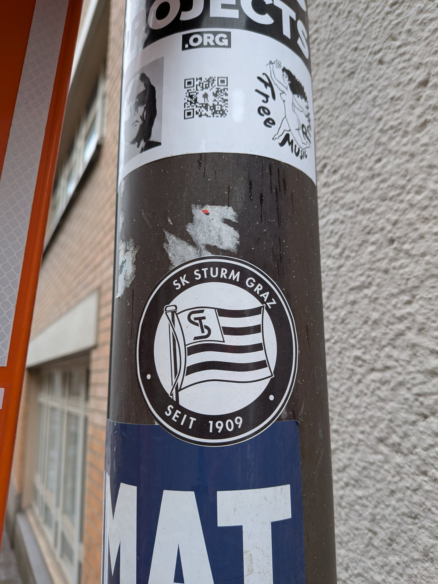 The sticker is circular, predominantly black and white. It features a stylized flag with horizontal stripes and a prominent 'ST' monogram in the upper left canton, waving on a flagpole. The flag is centered within a white circle. Around the inner edge of the black border, the text 'SK STURM GRAZ' is written at the top, and 'SEIT 1909' is written at the bottom, separated by small dots on either side. The overall design is a classic club emblem.