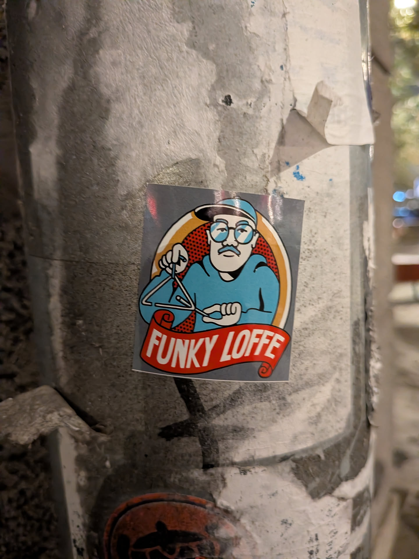 The sticker features a cartoon illustration of a man wearing glasses, a blue hat, and a blue shirt. He has a mustache and is holding a musical triangle with a beater. The illustration is enclosed in an oval with a red and white dotted background and an orange border. Below the oval, a red banner with white text reads 'FUNKY LOFFE'. The overall style is reminiscent of retro cartoons.