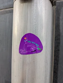 Street sticker An organic-shaped purple sticker depicting a white-outlined figure in a deep stretch. A small orange flower sprouts from its back, and it wears green socks. Green Swedish text 'VÄX ETT FRÖ' curves above the figure.