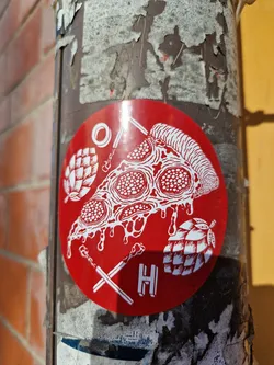Red round sticker with a pizza slice, hops, and matches. The letter H is in the bottom center. 