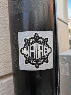 Street sticker A square sticker with a black circular emblem on a white background. The emblem features stylized white text reading 'NWA CREW' across the center, set against an eight-pointed star and a circular chain motif. Small text reads 'BS', '20', 'KASE', and 'DUBS' in the star's corners.