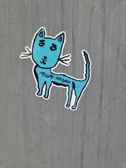 Street sticker A light blue sticker of a simple cartoon cat. The text 'MyGowan Skateboards' is written on the cat's body. 