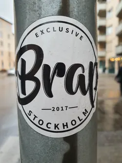 Street sticker A round white sticker with black text.  The word 'Brap' is prominently displayed in a stylized script font.  Above 'Brap', it says 'EXCLUSIVE' in a smaller font and below it says '-2017- STOCKHOLM'.