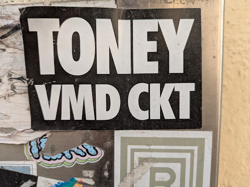 The sticker is black with white letters. The text reads "TONEY" on top and "VMD CKT" below it.