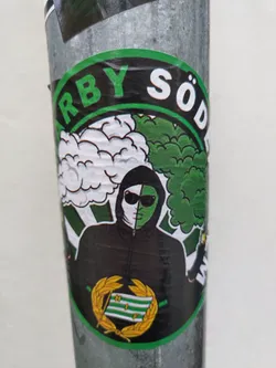 Street sticker A round sticker with a green and white color scheme. It depicts a stylized figure wearing a hooded jacket and sunglasses, partially obscured by white and green clouds. The text "ARBY SÖD" is prominently displayed in a circular banner at the top. The sticker also features a laurel wreath emblem at the bottom. The style is reminiscent of street art.