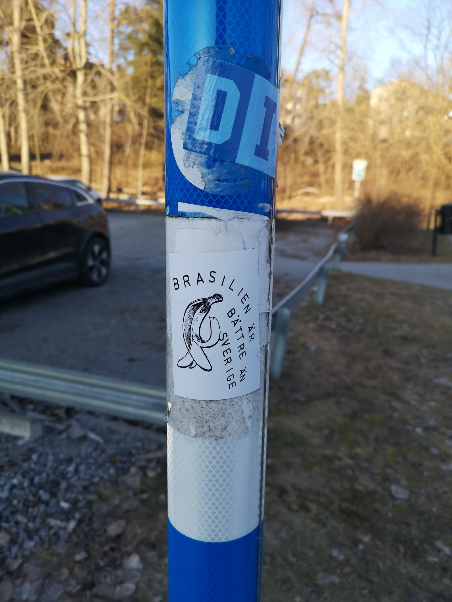 A rectangular white sticker featuring a black outline drawing of a creature resembling a dolphin or whale, but distinctly shaped like a peeled banana. The creature has an eye and a mouth. To the left of the creature, the word 'BRASILIEN' is written vertically in black capital letters. Above the creature, 'ÄR BÄTTRE ÄN' is written horizontally. To the right of the creature, 'SVERIGE' is written vertically in black capital letters. The overall style is simple and monochrome.