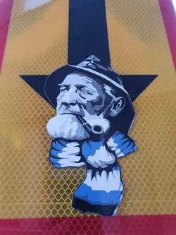 Street sticker This sticker is a striking piece of street art, featuring a bold graphic design of a weathered man with a pipe, seemingly wearing a hat and scarf.  The color palette is limited to blues, grays, and black, making the image stand out against any background. The style is reminiscent of screen printing or stencil art.