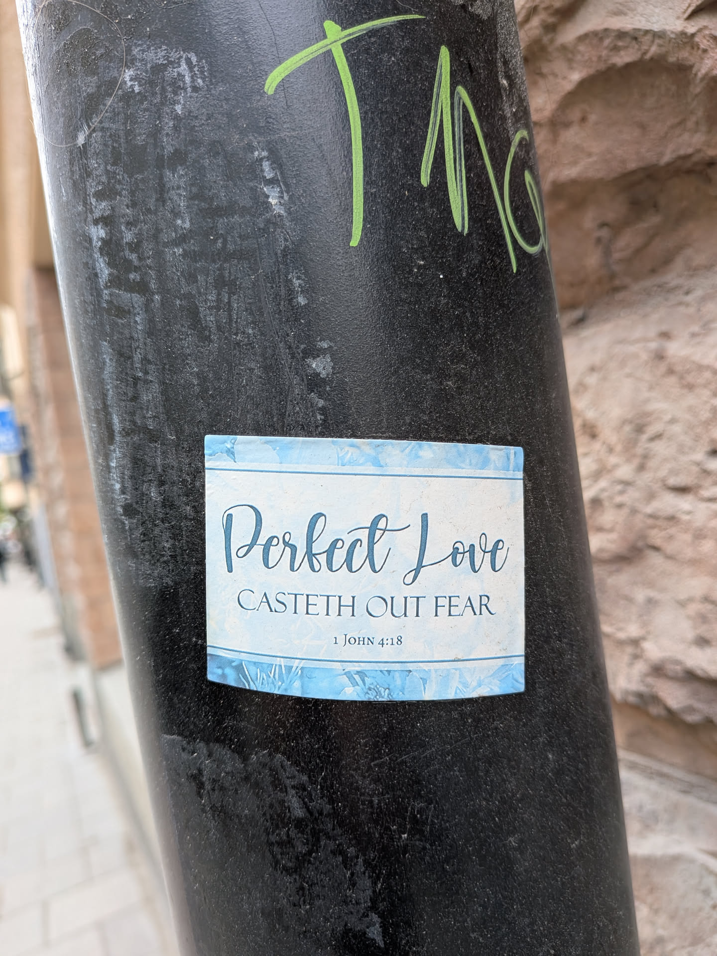 A rectangular sticker with a light blue, watercolor-like background. The top and bottom edges feature a decorative border with stylized blue floral or leaf patterns. The main text, 'Perfect Love', is written in a large, elegant script font in dark blue. Below it, 'CASTETH OUT FEAR' is in a smaller, all-caps serif font, also in dark blue. At the very bottom, '1 JOHN 4:18' is in a small, simple serif font. The sticker has a clean, spiritual, and calming aesthetic.