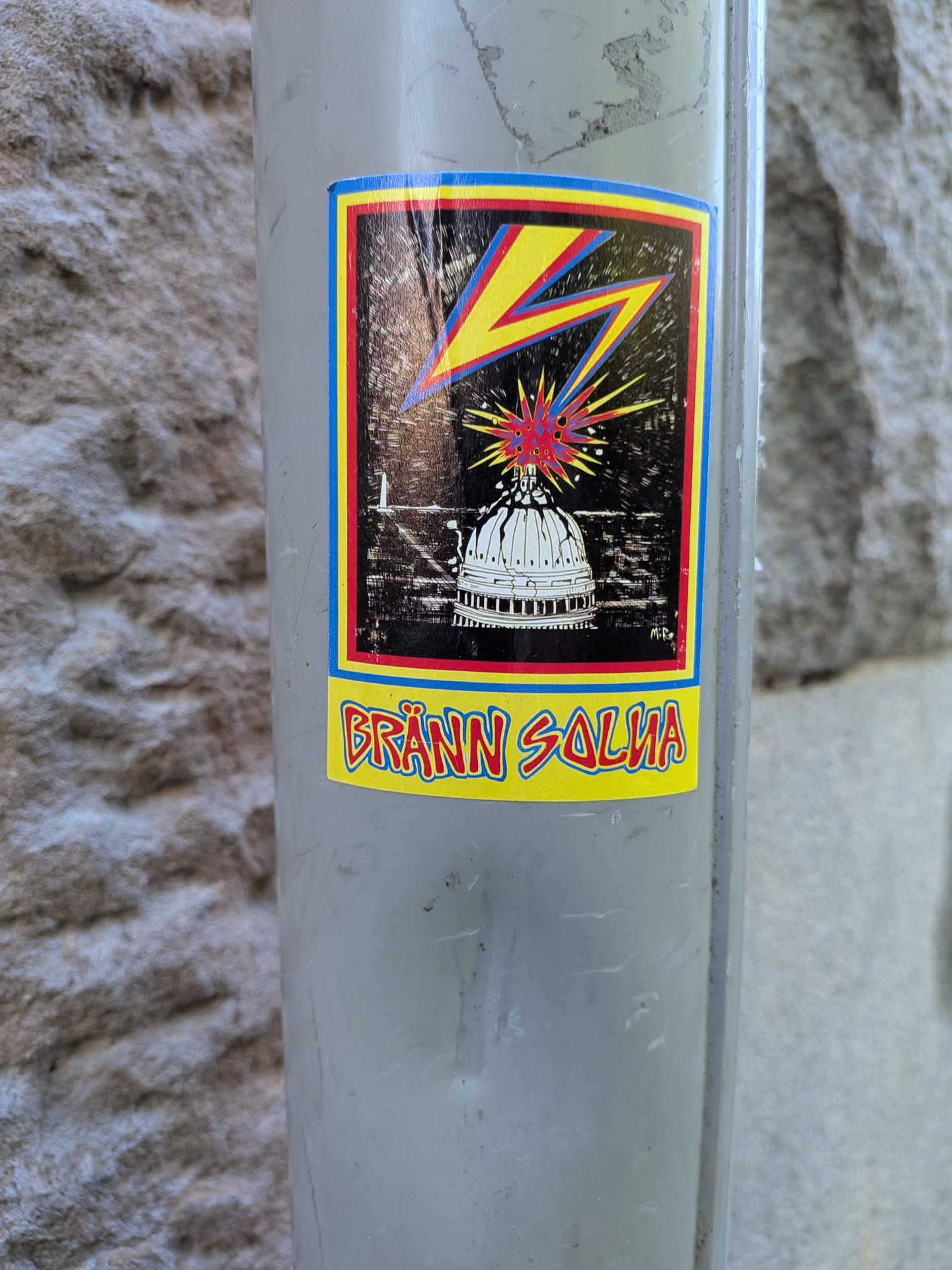 A rectangular sticker featuring a white dome struck by a yellow and red lightning bolt against a dark background. Below the illustration, the Swedish text 'BRÄNN SOLNA' is printed in stylized red letters on a yellow background.