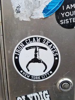 A black and white sticker of Iron Claw Skates, a company based in New York City. The sticker features an illustration of a claw-like object, possibly related to skating or a skating tool. 