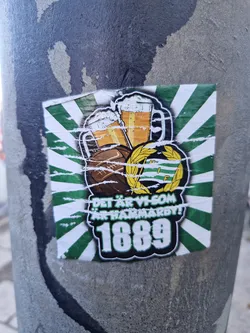 A worn Hammarby sticker featuring two beer steins, a soccer ball, and a laurel wreath. The text says "Det är vi som är Hammarby!" which translates to "It's us who are Hammarby!"  The year 1889 is prominently displayed, likely signifying a founding or significant year for the club.