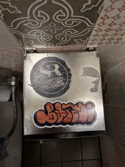 A sticker featuring graffiti-style text that looks like it's made of bricks.  There's also a smaller, circular sticker underneath featuring the logo for Selected Records.