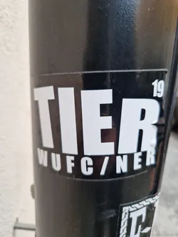 Street sticker Black and white sticker with the word TIER in large, bold, uppercase letters. Below it, in a smaller font, is the text "WUFC/NER." The number "19" is visible in the upper right corner.