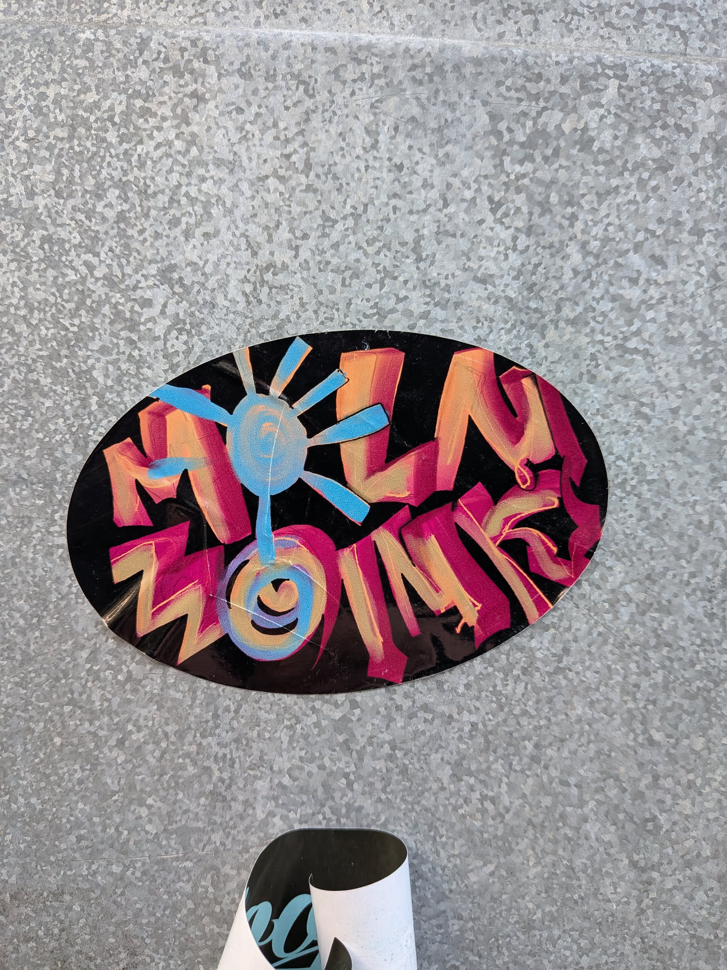 An oval-shaped sticker with a glossy black background, featuring bold, stylized graffiti lettering that spells 'FUN ZONE'. The letters are rendered in vibrant shades of pink, orange, and yellow, with bright blue accents and outlines. A stylized sun symbol, primarily in light blue and yellow, is integrated into the design, replacing the 'O' in 'ZONE' and adding a dynamic, energetic focal point. The overall appearance is colorful and energetic, reminiscent of street art.