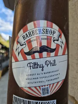 Street sticker Sticker for Honest Al's Barbershop, located at Wollmar Yxkullsgtan 9.  Features a vintage barbershop design with a mustache and red and white stripes. Includes a QR code and Instagram handle.
