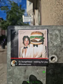 Street sticker A sticker featuring a picture of a person with a burger for a head, dressed in formal wear. The text below the picture says "DJ burgerhead - waiting for you #housemusic".