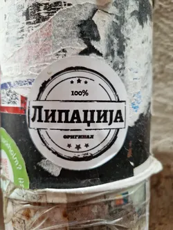 Street sticker A round sticker with the text "Липација" in the center and "100%" and "оригинал" above and below respectively, all within a circular border with three stars.