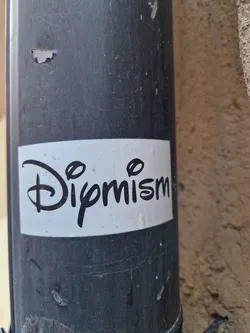 Street sticker A white sticker with black text on a dark grey pipe. The text is stylized and says "Dipmism".
