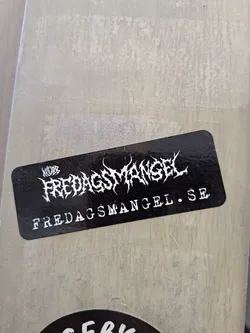 Street sticker A rectangular black sticker with rounded corners. Features white, spiky death-metal style typography reading 'KLUBB FREDAGSMANGEL' and the website 'FREDAGSMANGEL.SE' below.