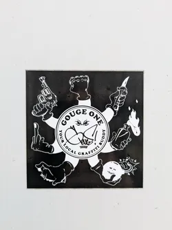 Street sticker The sticker showcases a design with arms extending outwards, each hand holding a different object like a gun, knife, Molotov cocktail, and a skull. The central circle reads 'GOUGE ONE' and 'YOUR LOCAL GRAFFITI BUDDY'. The style is reminiscent of stencil art, with stark black and white contrast.