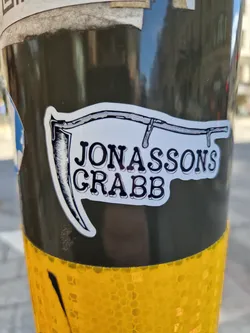 A sticker featuring a drawing of a scythe and the text "JONASSONS GRABB".