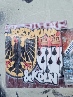 Street sticker A sticker featuring a graffiti-style design combining the coats of arms of Dortmund and Cologne, Germany.  The design includes stylized text and drips, giving it a street art aesthetic.