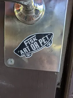 Street sticker A black, skateboard-shaped sticker mimicking the Vans logo, featuring white text 'FISK' and 'ART OR PET' with a white border.