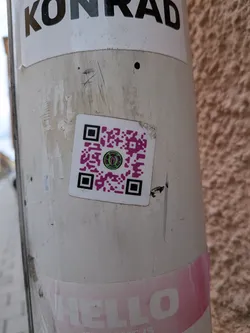 Street sticker A square-shaped sticker with a white border, featuring a prominent QR code. The QR code pattern is rendered in a bright magenta color against the white background. At its center, there is a circular logo depicting a stylized green eye with a black pupil, surrounded by a black outline. The eye has a somewhat reptilian or alien appearance. Around the eye, in very small white text on a black background, are the words 'MONEY STUFF'.