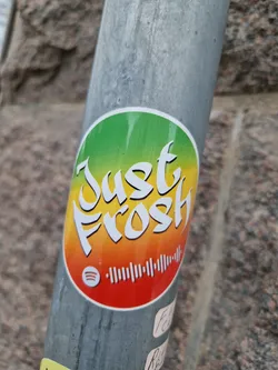 Street sticker A round sticker with a green, yellow and red gradient background. The text 'Just Frosh' is written in a stylized font. There is a Spotify code at the bottom of the sticker.