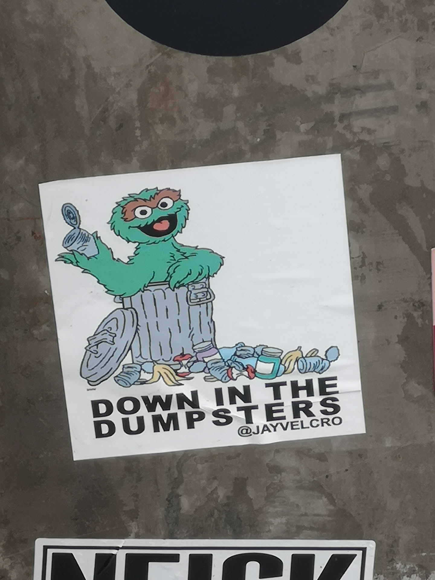Square white sticker depicting Oscar the Grouch in a trash can holding a tin can, surrounded by litter. Bold black text below reads 'DOWN IN THE DUMPSTERS' with the handle '@JAYVELCRO'.