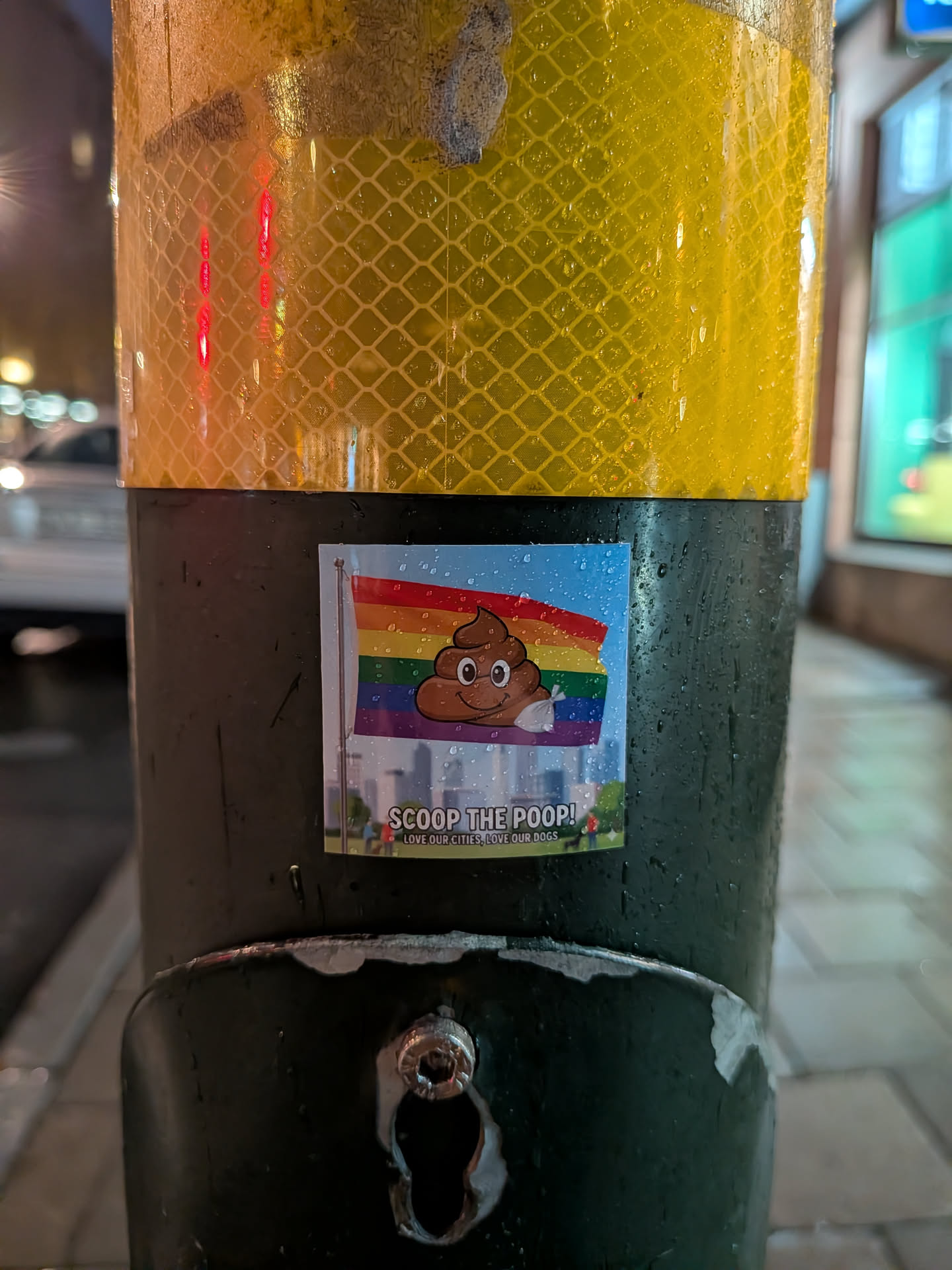 The sticker features a cartoon poop emoji with a smiling face, holding a white bag in its hand. Behind the emoji is a rainbow flag, with a cityscape visible at the bottom. The text 'SCOOP THE POOP!' is prominently displayed, followed by smaller text 'LOVE OUR CITIES, LOVE OUR DOGS.' The overall design is colorful and humorous, combining elements of LGBTQ+ pride with a message about responsible pet ownership.