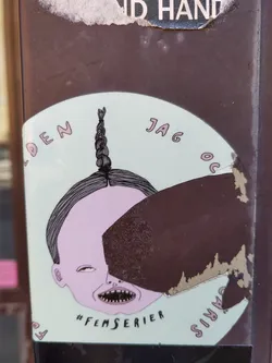 Street sticker Round sticker with a pastel green background featuring a stylized illustration. A character's head with a braid is depicted, partially obscured by a dark brown irregular shape. Text in a pale pink font surrounds the illustration, and the hashtag #femserier is visible beneath it. The sticker shows some wear and tear, with edges slightly damaged.