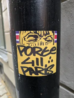 Street sticker Yellow sticker with black graffiti art of a face wearing a balaclava.  The text 'POREE 411 PARIS' is written below the image. A small flag is visible in the upper left corner of the sticker.