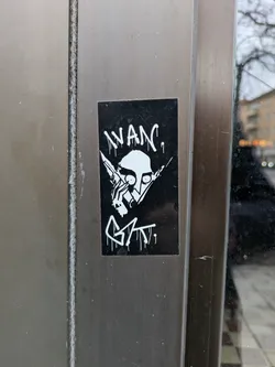 Street sticker Black and white sticker with a graphic design. It features a character with pointy ears, holding what seems to be syringes near the face. The text 'WANc.' is written above the character, and a tag 'GAT.' is visible below. 