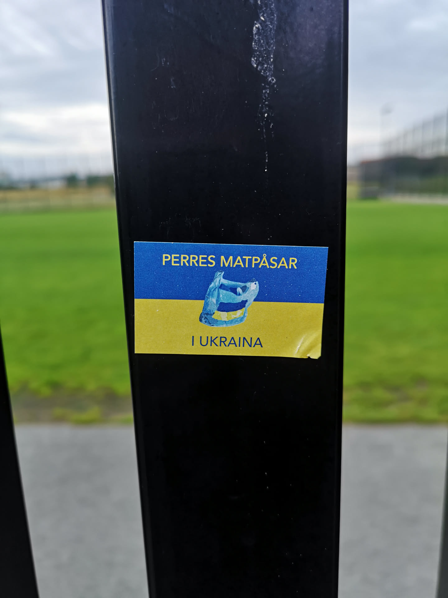 Rectangular sticker with Ukrainian flag colors. Features Swedish text 'PERRES MATPÅSAR I UKRAINA' and a central illustration of a blue plastic bag.
