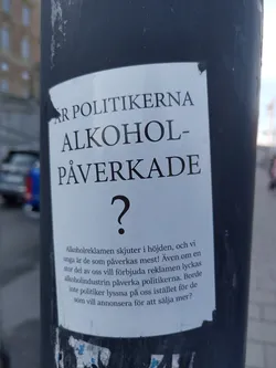 Street sticker A sticker expressing concern about the alcohol industry's influence on politicians and the impact of alcohol advertising on young people.  The sticker is predominantly white with black text in Swedish.