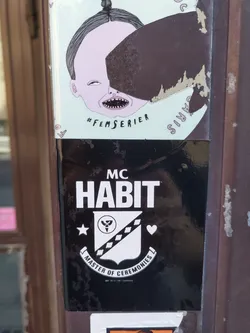 Black and white sticker with the text "MC HABIT" in bold letters above a crest containing a symbol and a heart. Below the crest, it says "Master of Ceremonies".