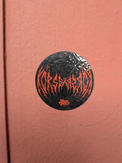 Street sticker A circular black sticker on a textured red wall. It features spiky red death-metal style text reading 'KORSEARZADA' and a smaller 'Beer Barons' logo below.