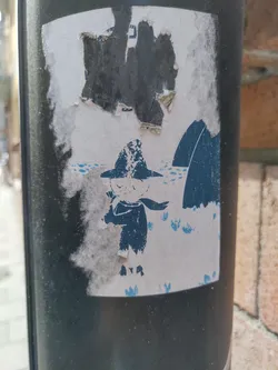 This weathered sticker features a simple yet captivating illustration. A small figure, dressed warmly in a hat and scarf, stands amidst small blue flowers and a dark background suggesting a snowy or icy setting. The sticker itself is slightly damaged, giving it a vintage feel.  No text or QR codes are visible.