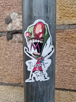 A sticker featuring Invader Zim in a vibrant, stylized design. The artwork is by Illgrafix Tattoo. The character is depicted with his signature wide eyes and menacing grin, arms outstretched in a playful yet slightly menacing pose.  The sticker is adhered to a metal pole.