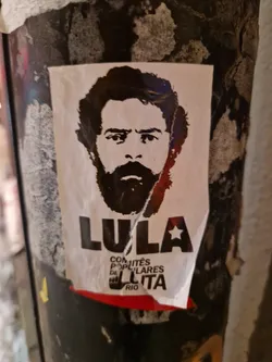 Street sticker A black and white sticker featuring a portrait of Luiz Inácio Lula da Silva, former president of Brazil. The sticker includes text in Portuguese that translates to "Lula - Popular Committees of Struggle Rio".