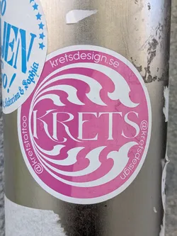 Street sticker This is a round pink and white Krets sticker, it features a stylized 'KRETS' in a decorative font, with 'kretsdesign.se' above and '@kretstattoo' and '@kretsdesign' around the edge.