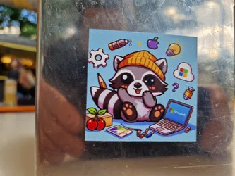 Street sticker A cute cartoon raccoon wearing a beanie is surrounded by various tech-related items such as a laptop, lightbulb, cloud storage icon and cherries. The overall style is reminiscent of kawaii and digital art.