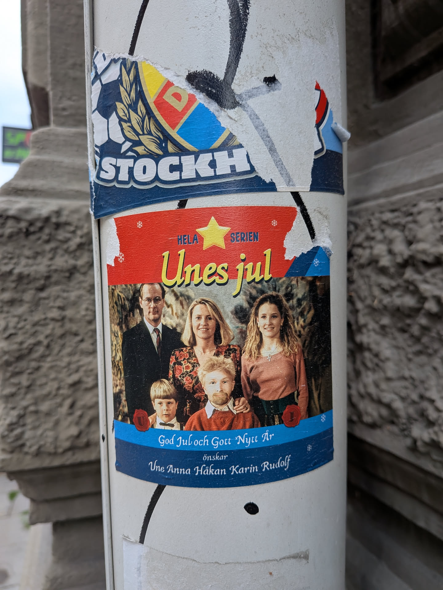 A rectangular sticker depicting a family portrait parody. The top is red with a yellow star and the title 'Unes jul'. The center photo shows a family where one child has a bearded man's face. The bottom is blue with Swedish holiday greetings.