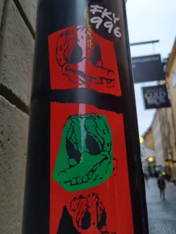 Street sticker A sticker featuring two cartoon duck heads, one red and one green, with a creepy expression. They're on a red background with some additional black elements at the bottom. Another sticker above it says "fky 996".