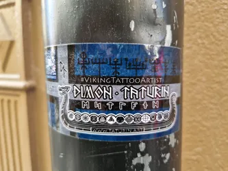 Street sticker Sticker featuring a Viking ship, runes, and the artist's name and tagline. The design is predominantly blue and silver with black details.