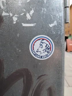 A circular sticker with a white background. It features a central illustration of a bearded man wearing a cap, rendered in dark blue and white. The illustration is enclosed by concentric circles in light blue, red, and dark blue. The text 'SUPTRAS ROSTOCK' is written in white capital letters along the bottom curve of the dark blue circle.