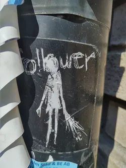 A black and white sticker featuring a stylized figure with the word 'Follower' above it. The style is somewhat reminiscent of minimalist line art or a sketch.  The sticker is adhered to a dark-colored cylindrical surface.