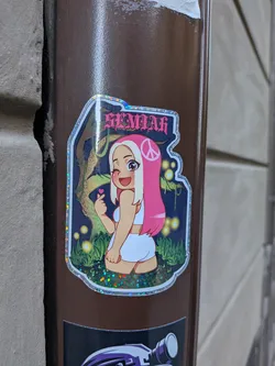 Street sticker A custom-shaped sticker featuring an anime-style girl with long, bright pink hair that fades to blonde, adorned with a pink peace sign symbol. She has large brown eyes, is winking with her right eye, and smiling. She wears a white crop top and white shorts, and is making a 'finger heart' gesture with her left hand, with a small pink heart symbol above it. The background is a dark, stylized fantasy forest scene with a gnarled tree trunk or vine on the left, green foliage at the bottom, and numerous glowing yellow-orange lights scattered throughout. The sticker has a prominent, shimmering holographic border that reflects rainbow colors. At the top, in a stylized gothic-like font, is the word 'GEMILAH' in pink with a darker outline.